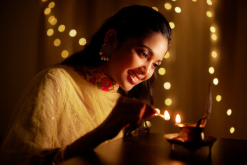 Obraz na płótnie Canvas Beautiful Hindu Indian young women lightening Deepa on Diwali day.
