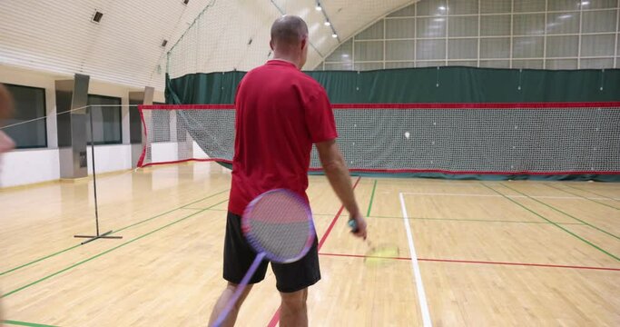 Training with rackets and shuttlecock on badminton court. Caucasian sportsman's playing badminton in gym. Playing badminton.