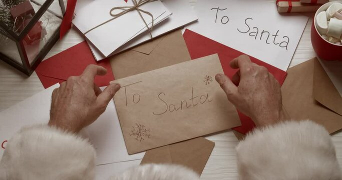 Santa Claus reading letters from children at table, top view