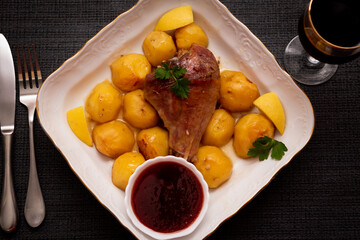 Turkey leg baked with potatoes with cranberry sauce. Delicious food.