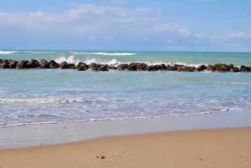 Sandy beach with wave breakers and blue sky. Room for copy space. Sciacca, Sicily, Italy. - obrazy, fototapety, plakaty