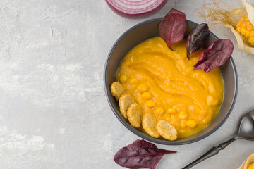 Delicious food for vegans and vegetarians. Creamy corn soup in a dark bowl on a light background. Healthy diet. Top view. Copy space