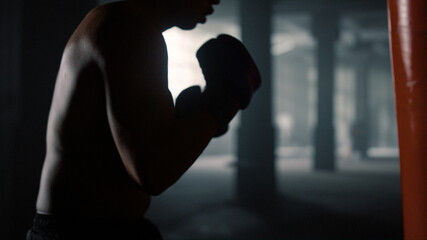 Man actively moving during training. Boxer boxing with punch bag
