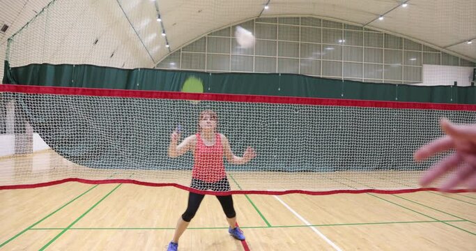 Training with rackets and shuttlecock on badminton court. Caucasian sportsman's playing badminton in gym. Playing badminton.