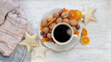 Fototapeta na wymiar Coffee cup, dried orange slices, nuts, decor stars and knitted sweater on rustic wooden table background. Christmas and New Year holiday. festive winter season. home cozy comfort. flat lay