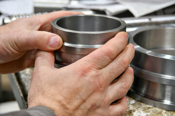 A worker holds the sleeve after cnc machining to measure and check for accuracy.