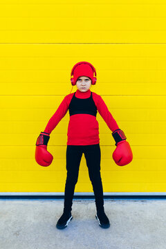 Girl in boxing gloves and hat standing near colorful wall
