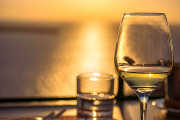 Glass of white wine against sunset with sea in background