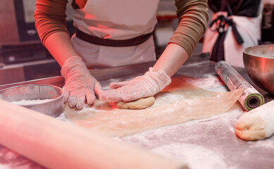 a female chef is working with a dough in the kitchen in a restaurant close-up of her hands. pizza preparation