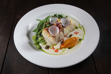 Pike perch with white sauce and beans. A white plate. Menu for the restaurant. A dish of eyelash fish. Healthy and low-calorie food.opy space. Flat lay.