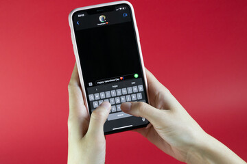 woman holding a smart phone and sending happy valentine's day