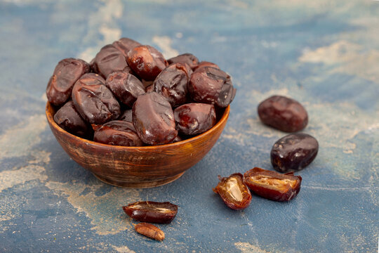 Dried dates in wooden bowl on blue background. Dates are excellent source of dietary fiber and essential minerals. Healthy fruit.