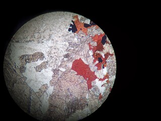 Colored sphere with vibrant colors in white, beige and ocher tones, seen under a microscope. Top view, abstract background. Black background.