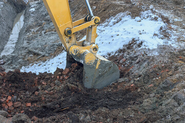 the process of loosening frozen winter soil with an excavator bucket
