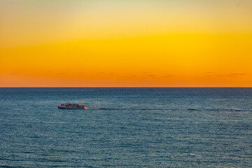 Naklejka premium Sochi, Russia, April 13, 2021. View of the sea at sunset time. Sailboat on the horizon
