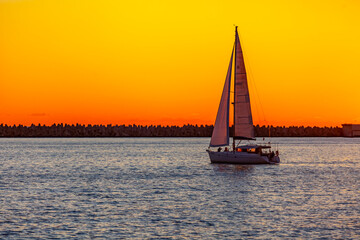 Fototapeta premium Sochi, Russia, April 13, 2021. View of the sea at sunset time. Sailboat on the horizon
