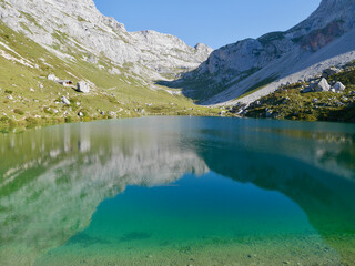 Reflection of mountains in emerald-green Lake Partnun in Praettigau, Graubuenden, Switzerland.