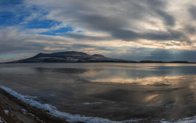 Winter landscape. Panorama of frozen lake Musov. In the background Palava - South Moravia - Czech Republic. There are dramatic clouds in the sky.
