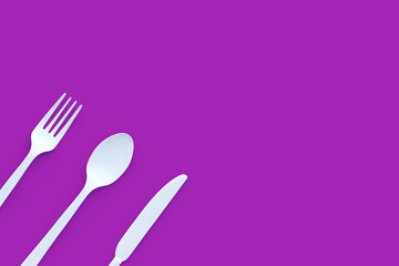 White fork, spoon and knife on violet background. Copy space. Top view. 3d render