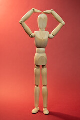 Wooden mannequin holding arms on the head, man had a headache, problems, picture on red background