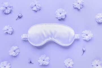 Color of the year 2022 Very Peri. Trendy color concept. Satin eye sleeping mask and fresh spring sakura flowers. Insomnia, sleeplessness disorder, beauty sleep. Close up, copy space, flat lay