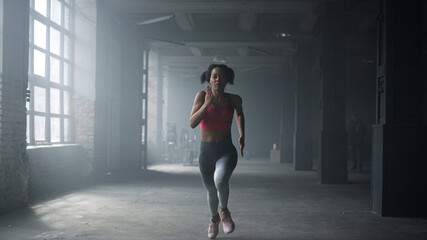 Fototapeta na wymiar Woman running fast in crossfit gym. Female athlete jogging in sport club