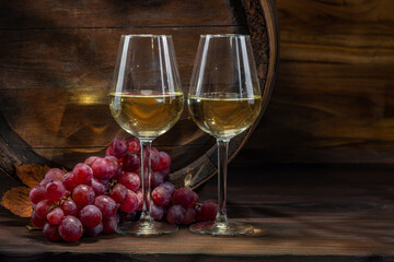 Wine glasses with tall stem. Old oak barrel in a dark wine cellar at the winery. Aging cellaring wine tasting