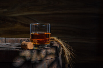 Glass decanter with whiskey, brandy on a vintage background of a rustic oaken barrel. Alcoholic beverage. Still life in the old style - obrazy, fototapety, plakaty