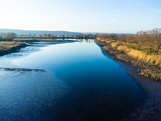Top down aerial view with early spring meadows, pond and river. 