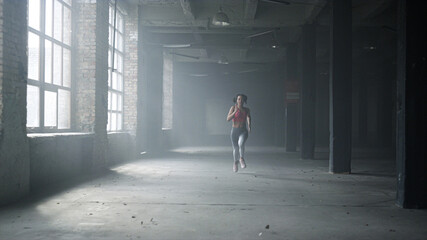 Fototapeta na wymiar Sportswoman training in loft building. Female jogger running in gym