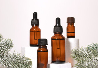 A mock-up of an empty glass dropper bottle made of brown glass stands on a white podium and a white background. Skin care serum, banner or template. The concept of a winter cosmetic product.Copyspace