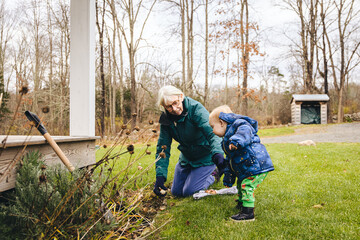 Grandmother plants bulbs in the front garden while her granddaughter looks on