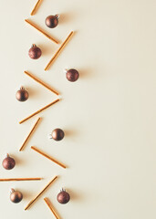 Minimal New Year concept. Christmas brown balls with gold straws on pastel yellow backgorund. Creative copy space.