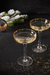 New Year champagne glasses and Christmas gold decorations on black background. Vertical composition. Close up.
