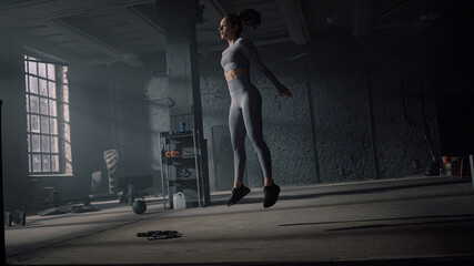 Fototapeta na wymiar Athlete doing deep squats with jumps. Powerful woman making buttocks workout