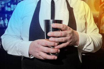 The hands of a professional bartender man holds a tool for mixing and making shaker cocktails