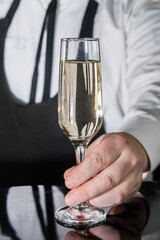 A professional bartender serves chilled champagne sparkling with gases in glass on the bar