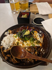 Thai food made of rice, mushrooms and tofu with delicious sauce. Wooden spoon with hot place on a table