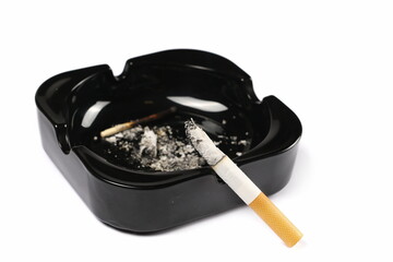 Lit cigarette in black ashtray isolated on white background