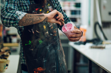 Male worker mixing colors for screen printing in a workshop
