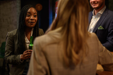 Woman drinking beer in the bar with her colleagues after work