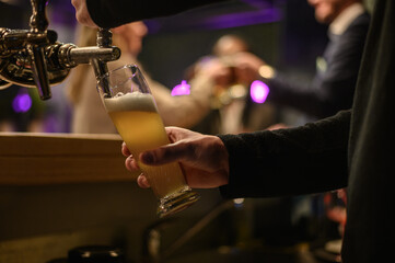 Hand of bartender using beer tap while working in a bar