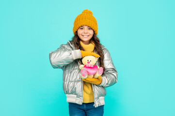 winter fashion. love toy for valentines day. happy kid in puffer jacket and hat. childhood.