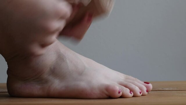 Person with a sprained ankle wrapping an elastic bandage around the swollen foot to reduce the swelling and improve recovery.