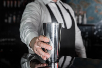 The hand of a professional bartender takes a tool for cooking and mixing alcoholic cocktail shaker, close-up