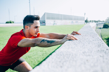Focused guy stretching legs preparing for workout