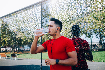 Fototapeta premium Sportsman drinking water after running workout in park