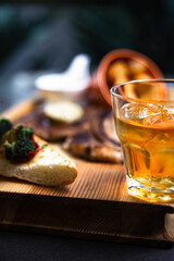 glass of whiskey. beef steak on wooden table close-up.