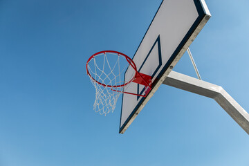 Basketball backboard with a ring on a blue sky background.
