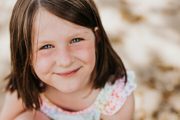Fototapeta premium Smiling girl with bright blue eyes and freckles looks at camera